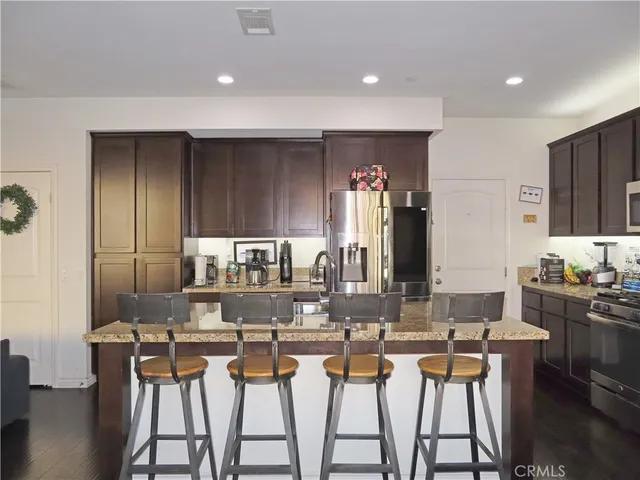 a dining hall with stainless steel appliances kitchen island granite countertop a dining table and chairs