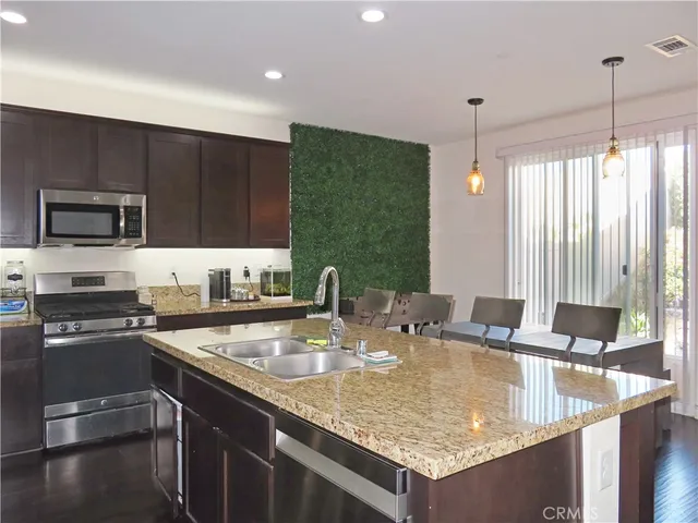 a kitchen with granite countertop a sink a counter top space appliances and cabinets