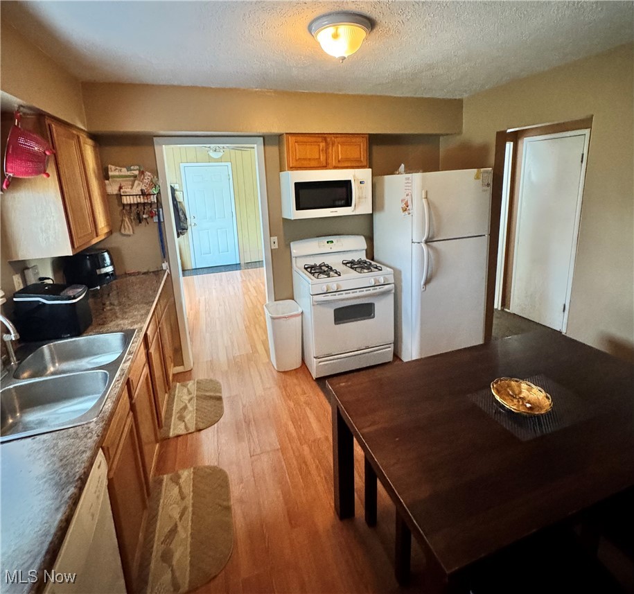 5945 Randy Road Bedford Heights, OH 44146 - Photo 6 of 13 Kitchen with white appliances, light wood-style floors, brown cabinets, a textured ceiling, and dark countertops