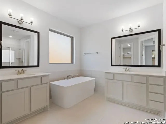 a bathroom with a double vanity sink mirror and bathtub