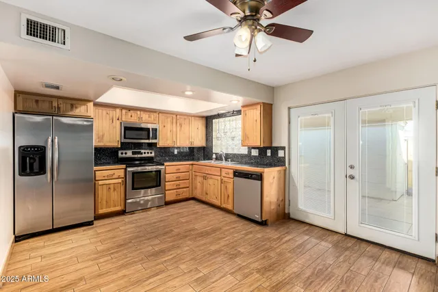 a kitchen with stainless steel appliances kitchen island granite countertop a refrigerator a sink a stove a microwave oven with white cabinets