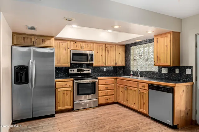 a kitchen with stainless steel appliances granite countertop a refrigerator a stove a sink and a microwave