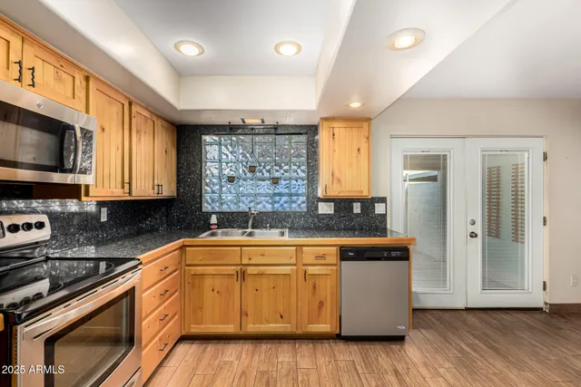 a kitchen with stainless steel appliances granite countertop wooden cabinets a stove a sink and a microwave