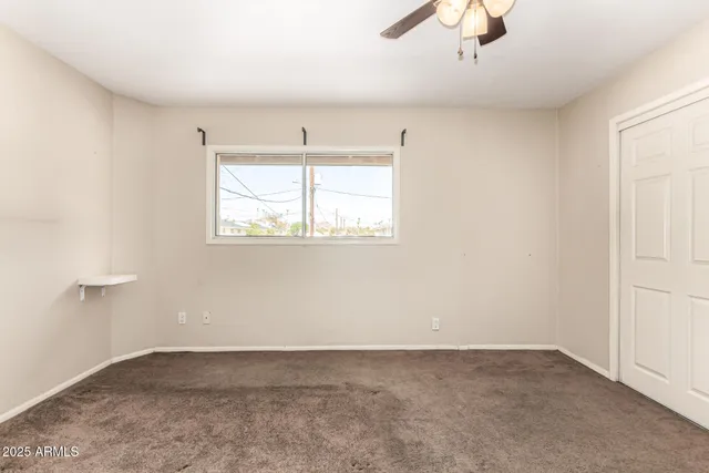 an empty room with windows and fan