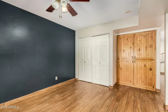 an empty room with wooden floor closet and windows