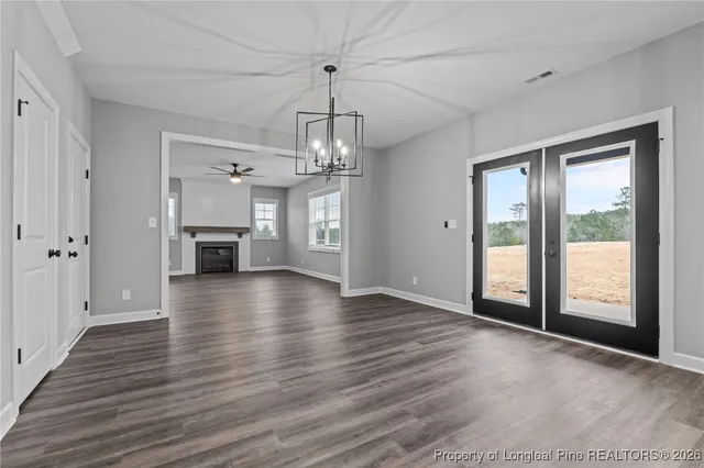 a view of an empty room with wooden floor fireplace and a window