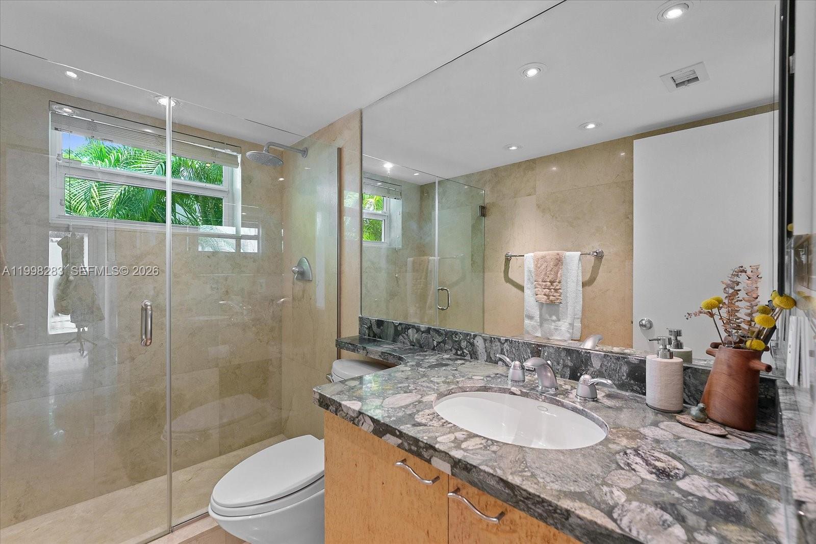 2721 Southwest 22nd Avenue, Unit A Miami, FL 33133 - Photo 19 of 36 a bathroom with a granite countertop sink a toilet a mirror and shower