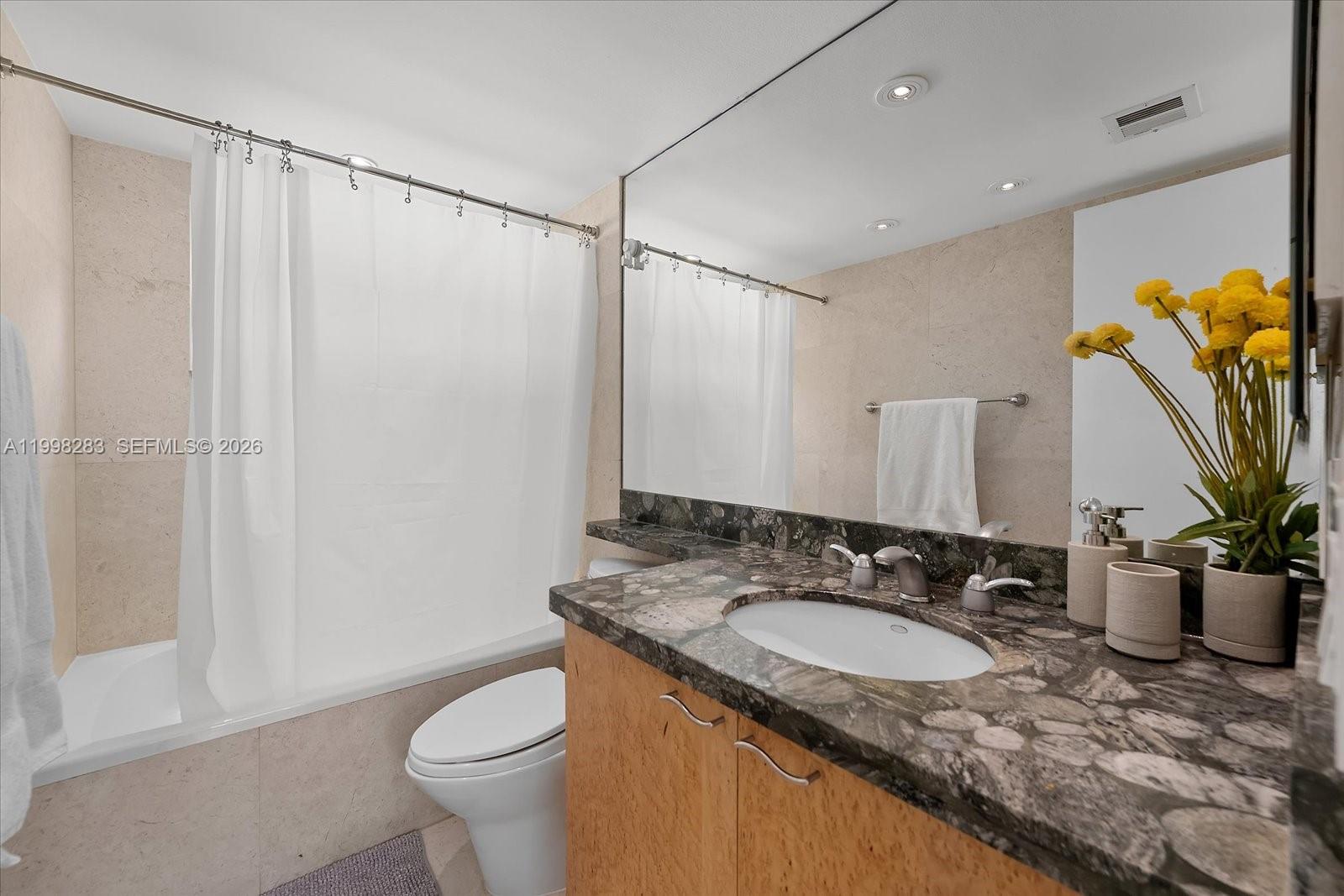 2721 Southwest 22nd Avenue, Unit A Miami, FL 33133 - Photo 31 of 36 a bathroom with a granite countertop sink a mirror and a toilet