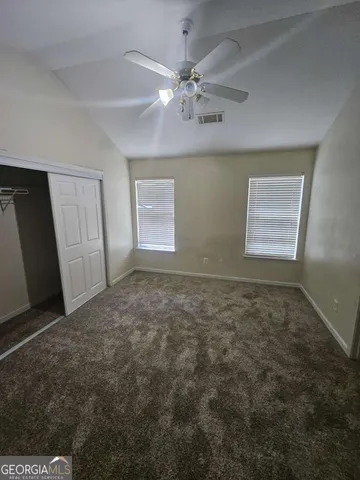 an empty room with windows and fan