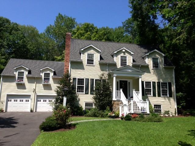 a front view of a house with a garden and trees