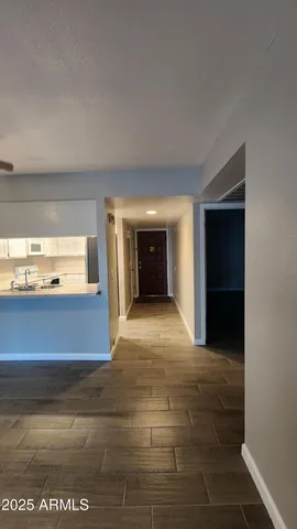 a view of an empty room with kitchen and window