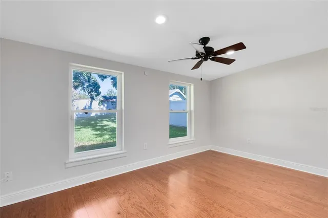 an empty room with windows and fan