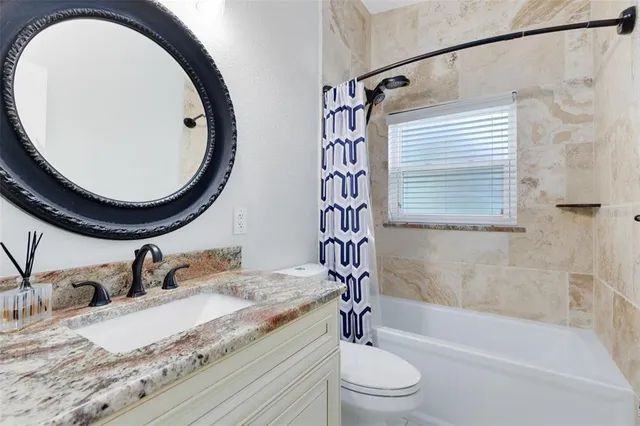 a bathroom with a granite countertop sink a toilet and a mirror