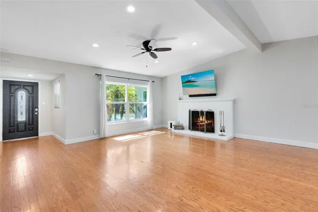 an empty room with windows fireplace and wooden floor