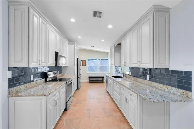 a large kitchen with stainless steel appliances kitchen island granite countertop a sink and cabinets