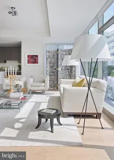 a living room with stainless steel appliances furniture a rug and a kitchen view