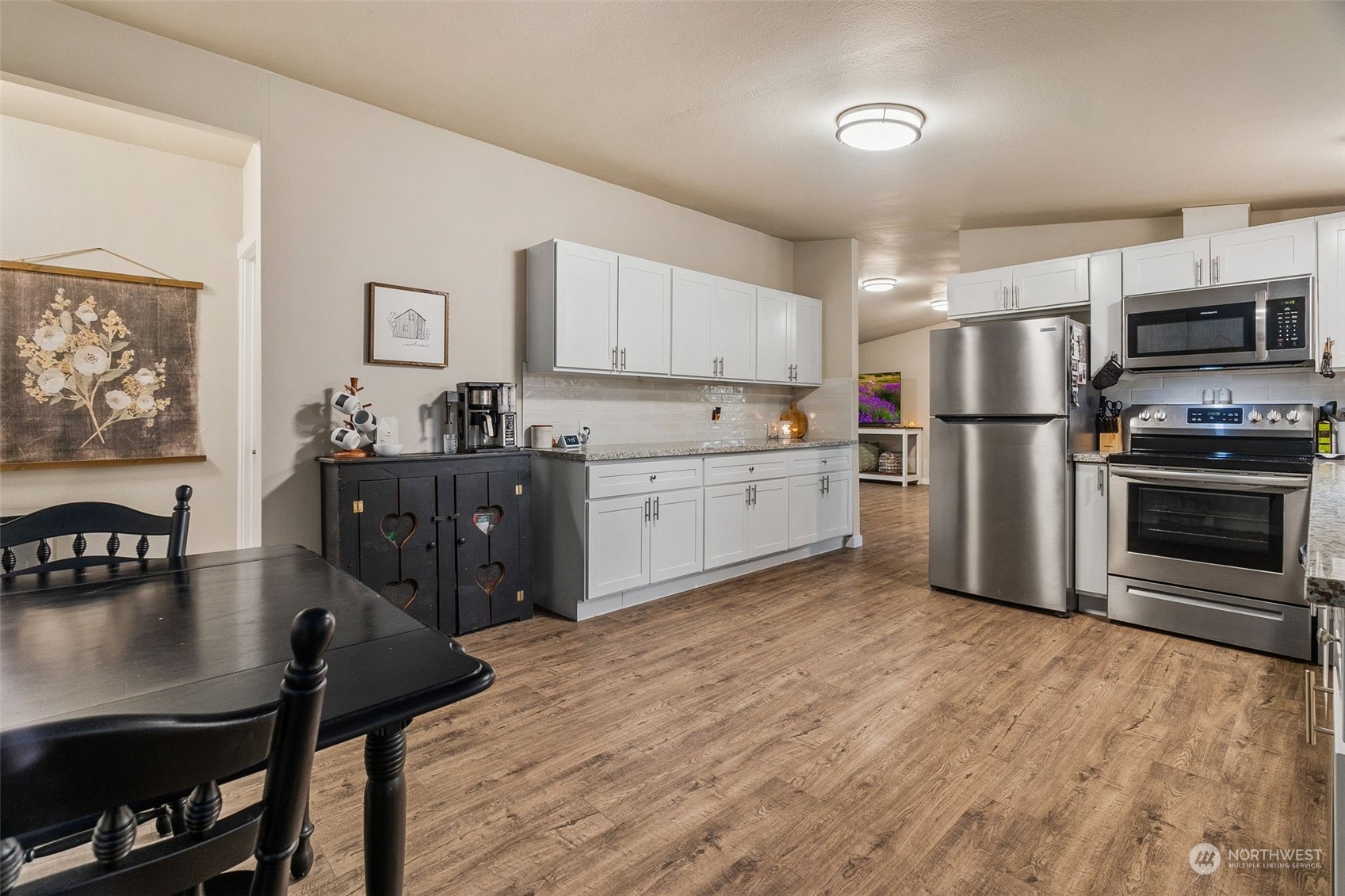 19025 Marble Street Southwest Rochester, WA 98579 - Photo 19 of 26 a kitchen with stainless steel appliances a stove a refrigerator a sink a dining table and chairs with wooden floor
