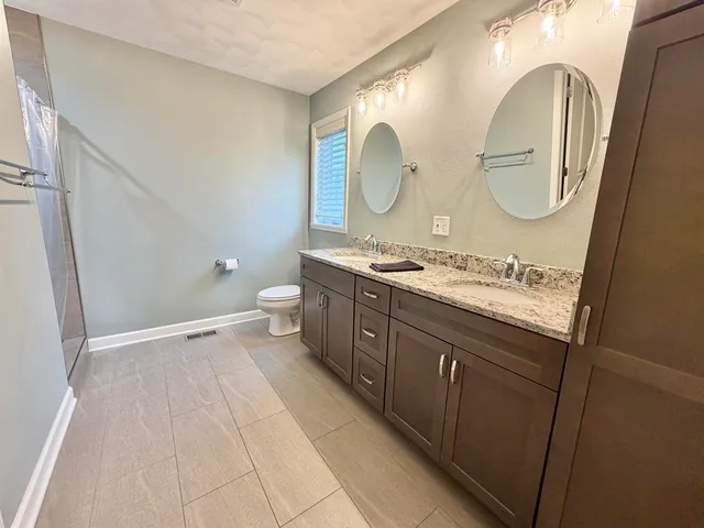 a spacious bathroom with a granite countertop sink mirror and a toilet