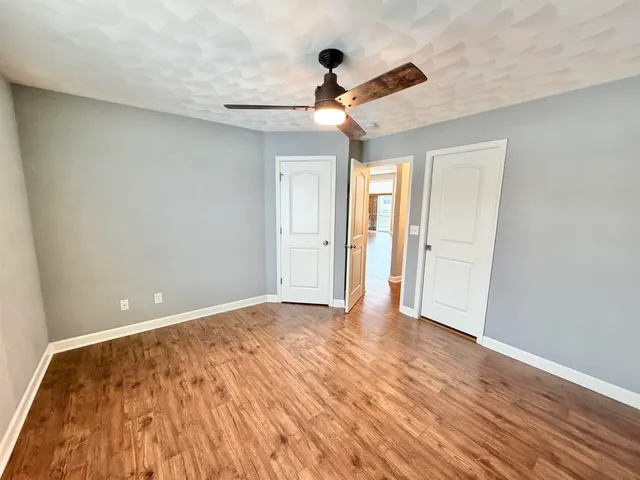 a view of empty room with wooden floor and ceiling fan