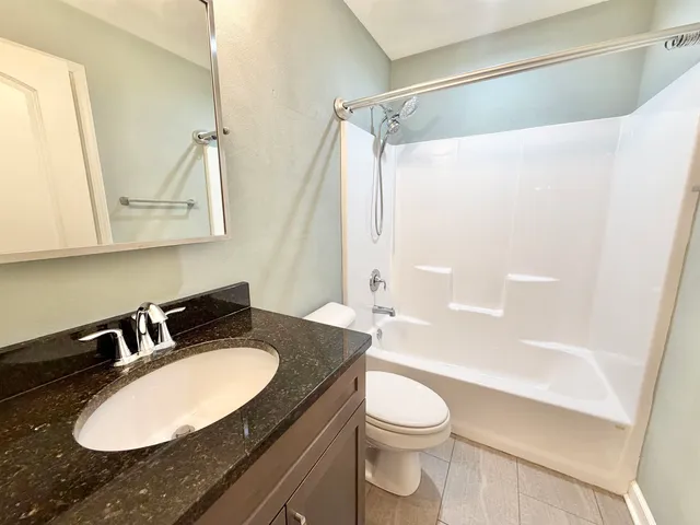 a bathroom with a granite countertop sink toilet a mirror and shower