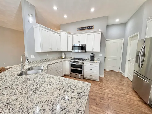 a kitchen with stainless steel appliances granite countertop a refrigerator sink stove and oven