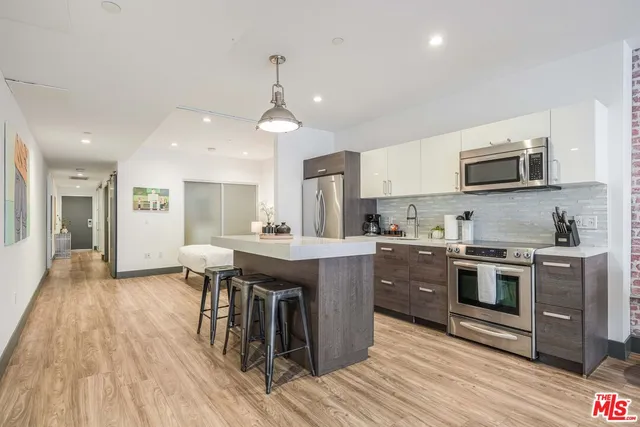 a kitchen with kitchen island granite countertop a sink and steel appliances