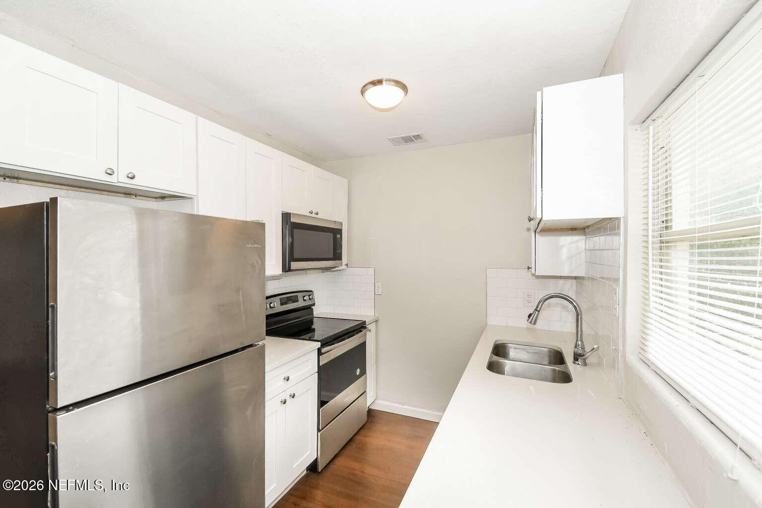 1480 Stimson Street Jacksonville, FL 32205 - Photo 17 of 21 a kitchen with stainless steel appliances a refrigerator sink and white cabinets