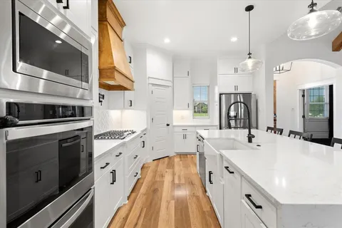 a large kitchen with stainless steel appliances a stove sink and cabinets