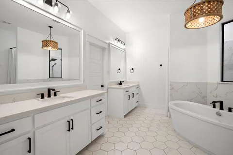 a bathroom with a double vanity sink mirror and bathtub