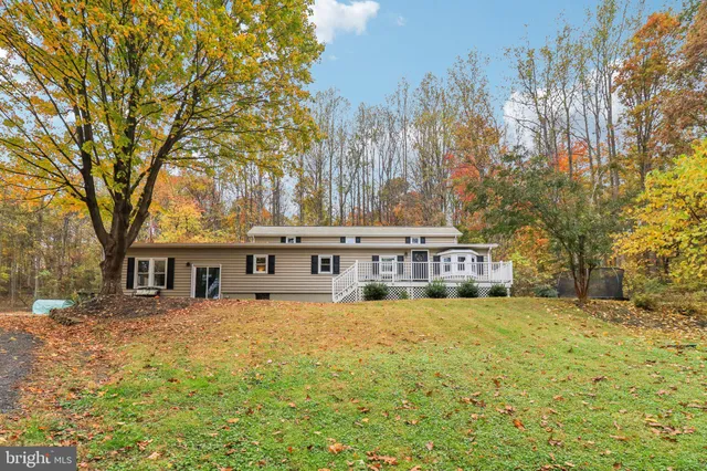 a view of a house with a big yard and large trees