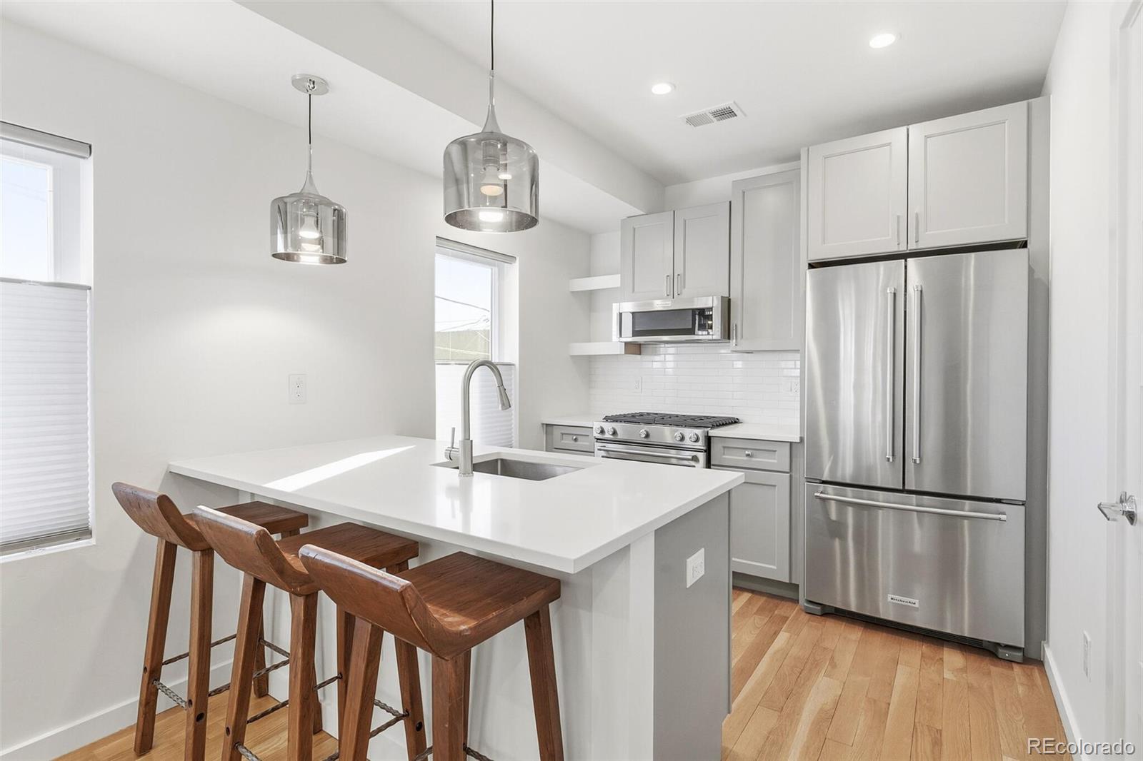 a kitchen with stainless steel appliances granite countertop a refrigerator a stove a sink dishwasher a dining table and chairs with wooden floor