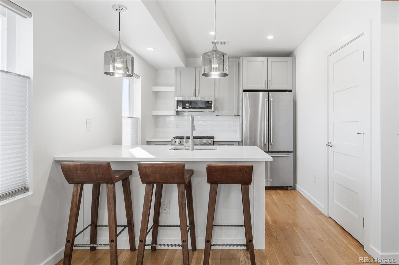 3850 West 13th Avenue Denver, CO 80204 - Photo 6 of 32 a kitchen with stainless steel appliances granite countertop a dining table chairs refrigerator and microwave
