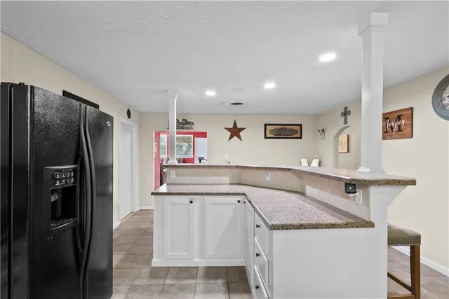 a kitchen with stainless steel appliances kitchen island granite countertop a dining table chairs and a refrigerator