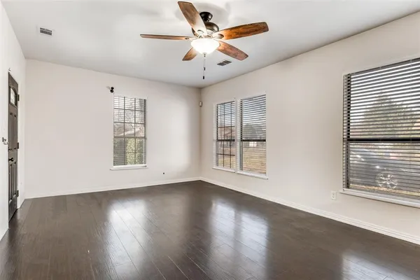 a view of an empty room with wooden floor and a window