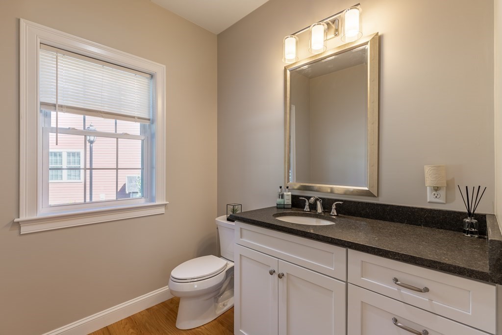 176 Main Street, Unit 3 Medway, MA 02053 - Photo 13 of 28 a bathroom with a granite countertop sink toilet and mirror