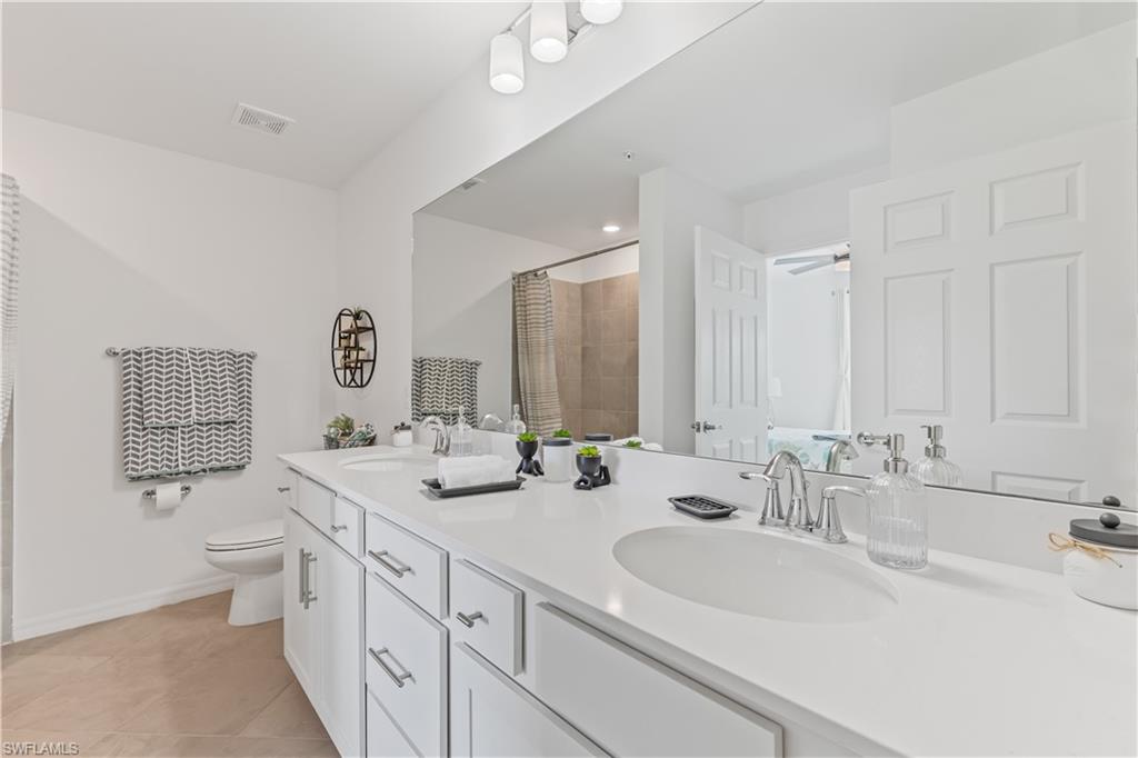 43997 Boardwalk Loop, Unit 1821 Babcock Ranch, FL 33982 - Photo 10 of 14 a bathroom with double vanity sinks a mirror and a shower