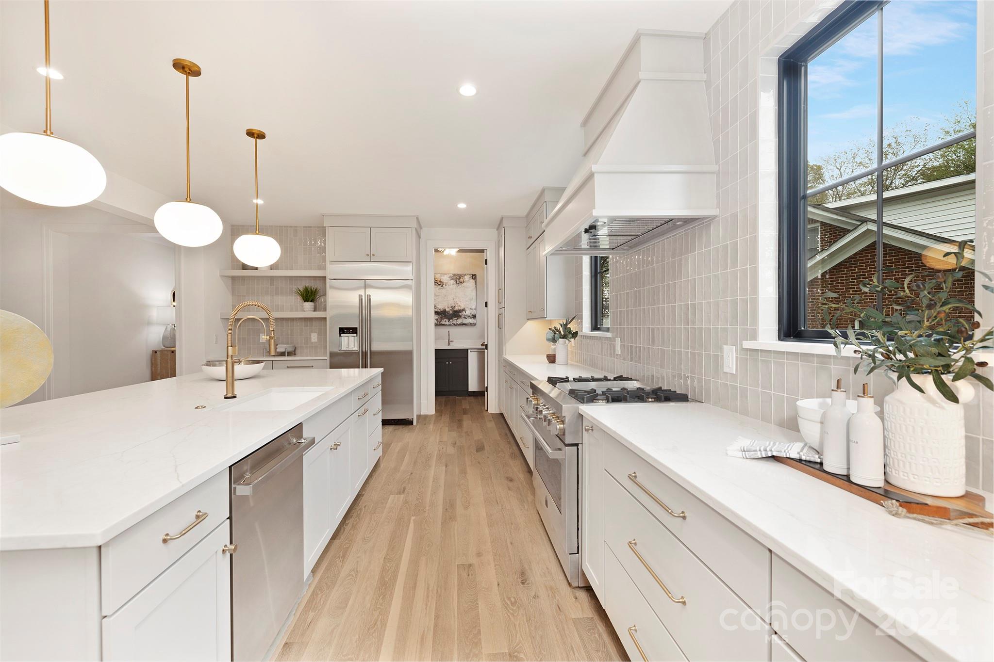 1815 Club Road Charlotte, NC 28205 - Photo 11 of 42 a large white kitchen with a stove oven a sink dishwasher and white cabinets with wooden floor