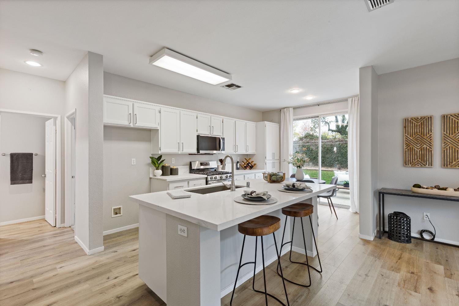 a kitchen with stainless steel appliances a stove a sink a refrigerator wooden floor cabinets and dining table