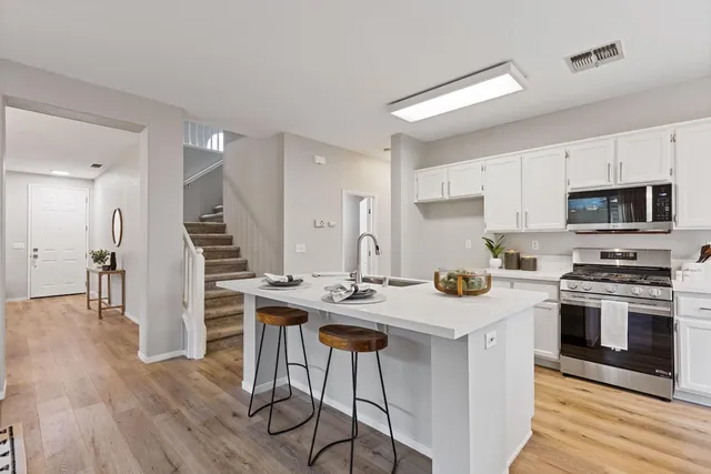 a kitchen with stainless steel appliances kitchen island granite countertop a stove a sink and a refrigerator