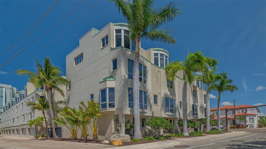 a front view of a multi story residential apartment building with a yard and potted plants