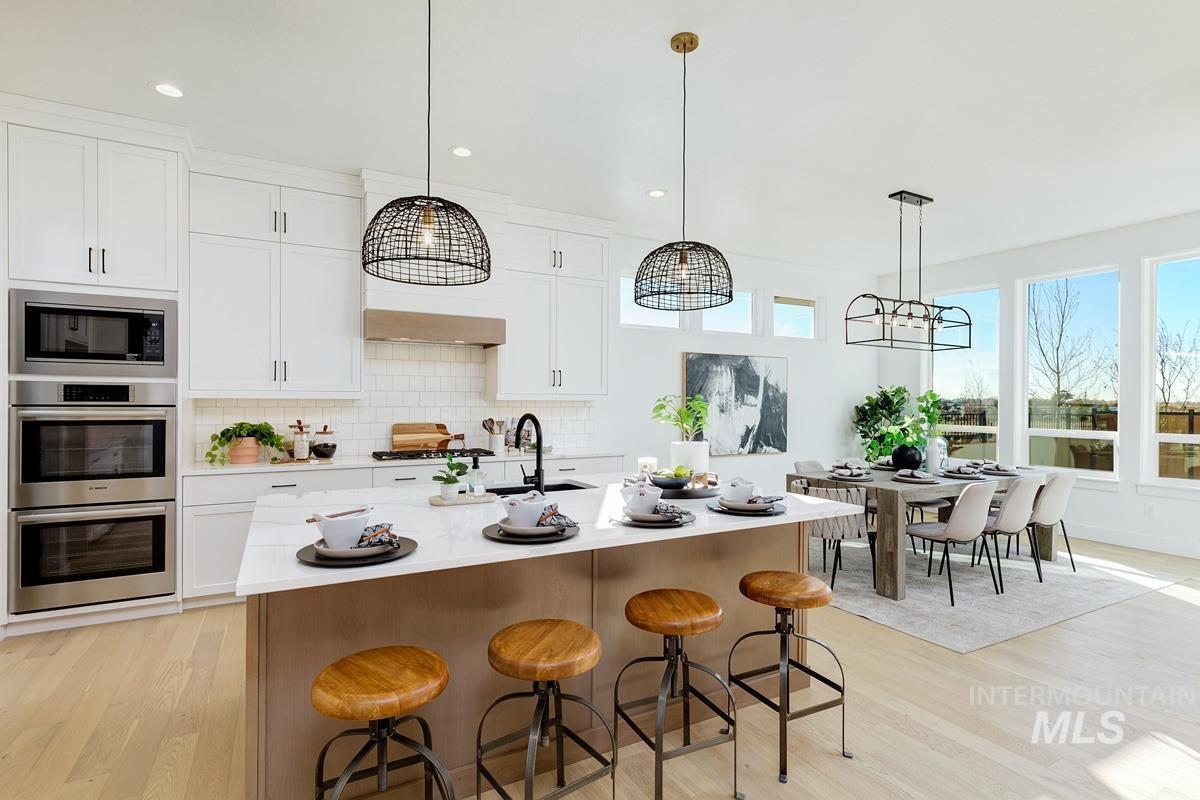 21895 Paint Avenue Star, ID 83669 - Photo 7 of 35 Kitchen with a breakfast bar area, pendant lighting, white cabinetry, tasteful backsplash, and light wood finished floors