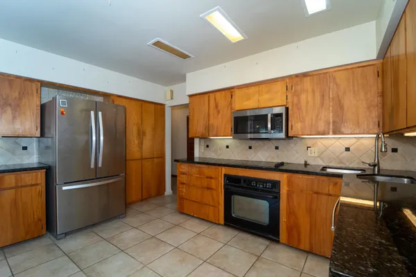 a kitchen with stainless steel appliances granite countertop a refrigerator and a stove top oven