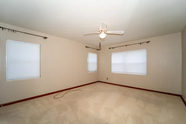 an empty room with windows and fan