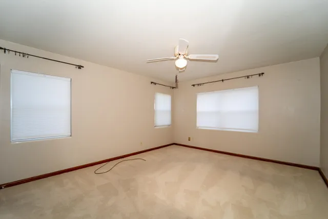 an empty room with windows and fan