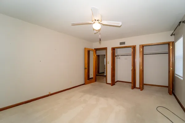 an empty room with closet and a ceiling fan