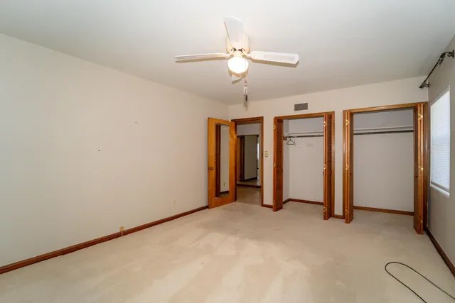 an empty room with closet and a ceiling fan