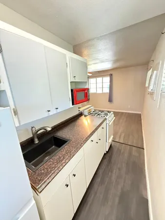 a kitchen with granite countertop a stove a sink and a refrigerator