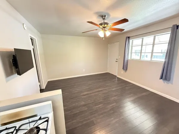 a view of an empty room with wooden floor and a window