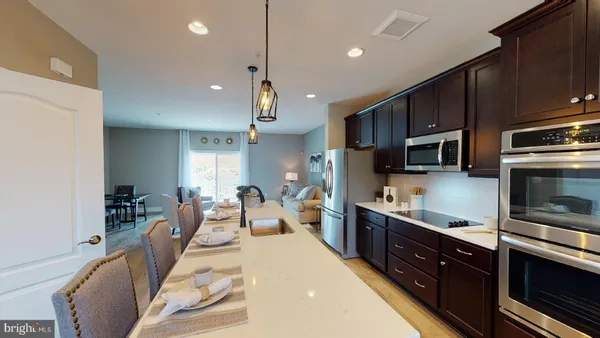 a open kitchen with stainless steel appliances granite countertop a sink a stove a refrigerator a center island a dining table and chairs