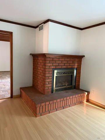 a view of an empty room with wooden floor and windows